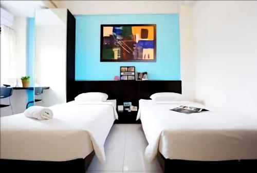 a room with two beds and a blue wall at LeGreen Suite Ratulangi in Ambon