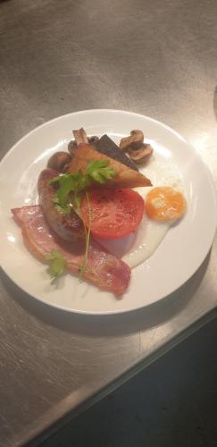 a plate of food with sausage and vegetables on a table at The Emmbrook Inn Hotel in Wokingham
