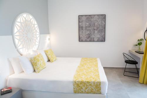 a white bed with yellow pillows in a room at Likio Studios in Batsi