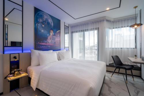 une chambre avec un grand lit blanc et un bureau dans l'établissement Ratri Hotel Phuket Old Town, à Phuket