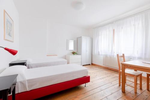 a bedroom with two beds and a table and a desk at Fondazione Lucia De Conz in San Gregorio nelle Alpi,