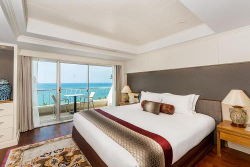 een slaapkamer met een groot bed en uitzicht op de oceaan bij Royal Wing Suites & Spa Pattaya in Pattaya South