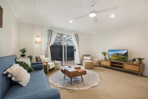 a living room with a blue couch and a tv at Spacious Family Beach House in Caloundra
