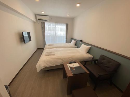 una habitación de hotel con 2 camas y una silla en HOTEL GranLeaf Miyakojima, en Isla Miyako