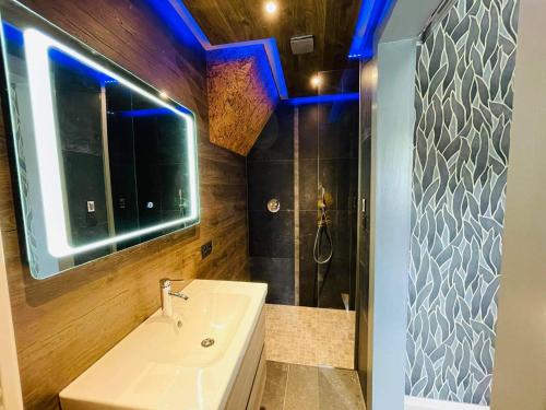 ein Badezimmer mit einem Waschbecken und einer Dusche mit blauen Lichtern in der Unterkunft Ol folle spa in Malmedy