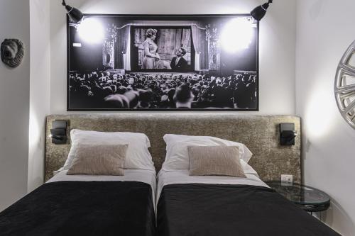 two beds in a room with a picture on the wall at Hotel CineApollo - Ogni camera un film! in Messina