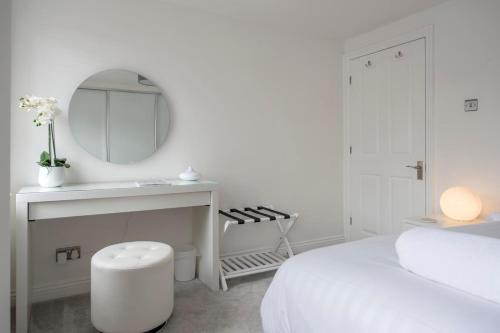a white bedroom with a white bed and a mirror at Penleys Apartment in York