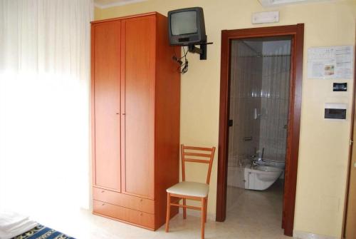 a bathroom with a toilet and a tv and a chair at Hotel Il Chierichetto in San Giovanni Rotondo