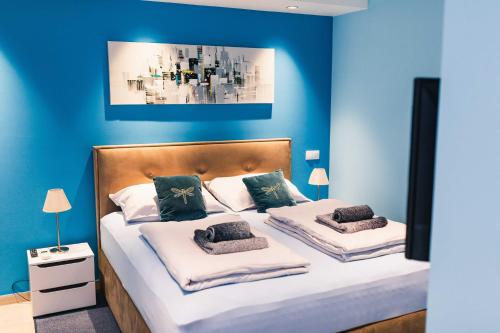 um quarto com paredes azuis e uma cama com duas almofadas em The Place Apartments Hebrangova em Zagreb