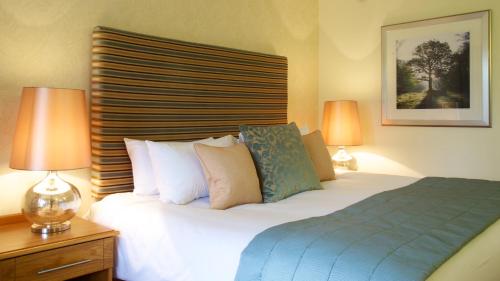 a bedroom with a bed with two lamps on a table at Marwell Hotel Winchester South in Winchester