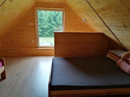 ein Bett in einem Zimmer mit Fenster in der Unterkunft Łemkowo Pokoje gościnne domek nr 2 in Lutowiska