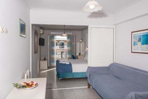a living room with a blue couch and a bed at Denise Beach Hotel in Laganas