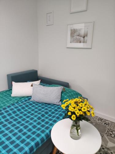 a room with a bed with a vase of flowers on a table at Apartament Letni Wiatr in Przewłoka