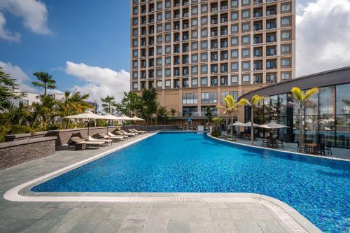 a large swimming pool in front of a tall building at Hotel Nikko Hai Phong in Hai Phong