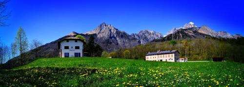 a house on a green hill with mountains in the background at Fondazione Lucia De Conz in San Gregorio nelle Alpi,