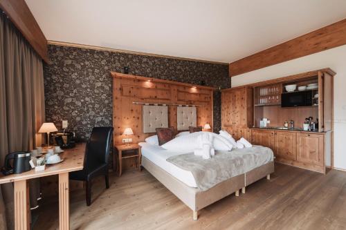 a bedroom with a large bed and a desk and a desk at Wellness Aparthotel Panorama Alpin - Ferienwohnungen Jerzens im Pitztal in Jerzens
