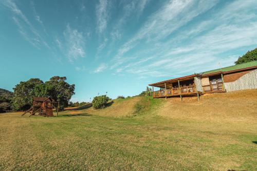 a house on top of a hill with a grass field at Thunzi Bush Lodge in Beachview