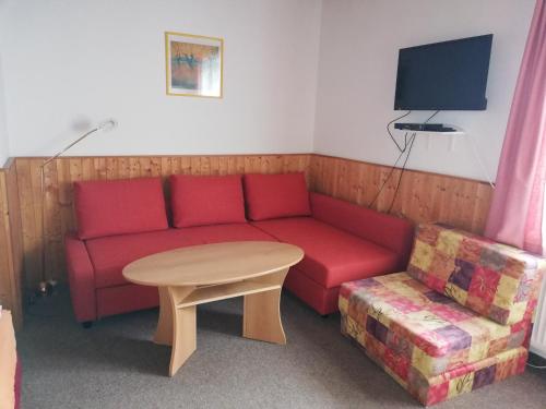 a living room with a red couch and a table at Ubytování Maxa in Špičák