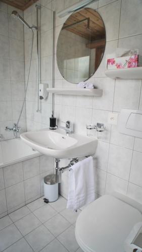 a bathroom with a sink and a toilet and a mirror at Hotel Wynegg in Klosters
