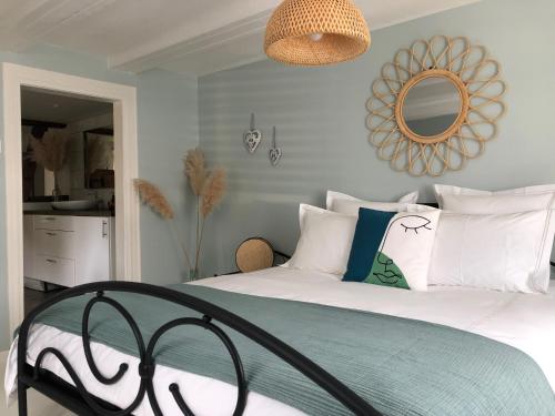 a bedroom with a bed with white pillows and a mirror at La Stube de Marinette 5 étoiles in Hipsheim