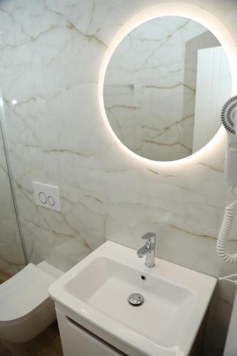a white bathroom with a sink and a mirror at Apartments Oda Hotel in Velipojë