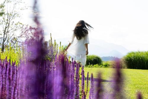 a young girl walking through a field of purple flowers at Hotel de Charme Laveno - Luxury all Inclusive in Laveno-Mombello