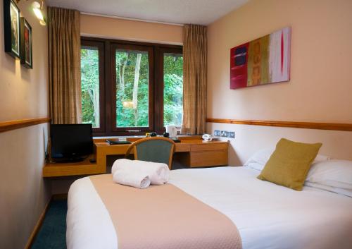 a room with a bed and a desk with a computer at The Coach House at Missenden Abbey in Great Missenden