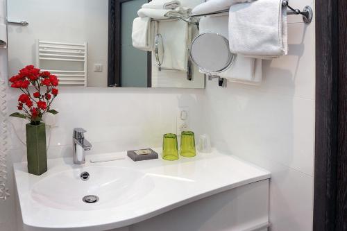 a white bathroom with a sink and a mirror at Logis Le Prieuré in Locronan