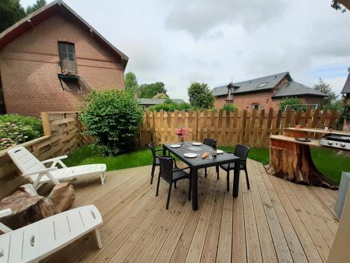 une terrasse en bois avec une table et des chaises. dans l'établissement les Gîtes du Château de Maltot, à Saint-Ouen-du-Breuil