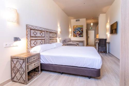 1 dormitorio con 1 cama blanca grande y 1 silla en Tarifa Suites by QHotels, en Tarifa