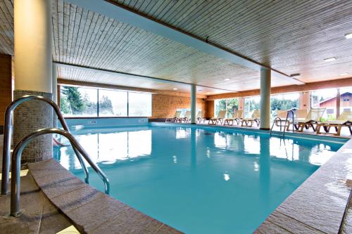 een groot zwembad met stoelen in een gebouw bij Village Vacances Le Grépillon in Les Rousses