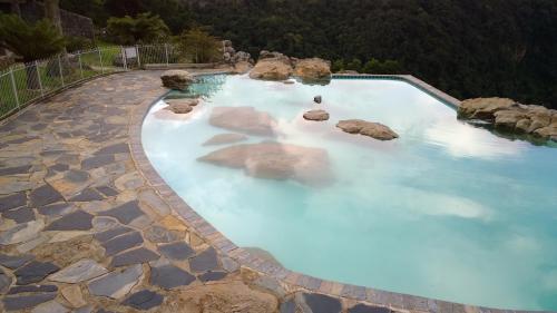 a swimming pool with blue water and rocks at Panorama Chalets & Rest Camp in Graskop