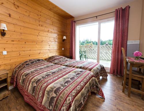 1 dormitorio con 1 cama y pared de madera en Village Vacances Le Grépillon, en Les Rousses