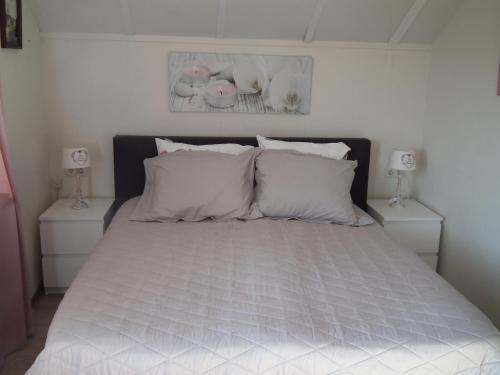 1 dormitorio con 1 cama con sábanas y almohadas blancas en B & B Kaaskenswater, en Zierikzee