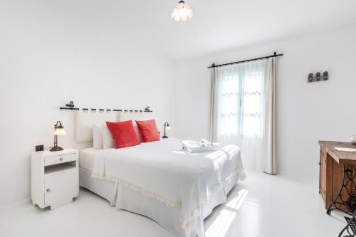a white bedroom with a large white bed with red pillows at Deniz Kabugu Hotel in Alacati