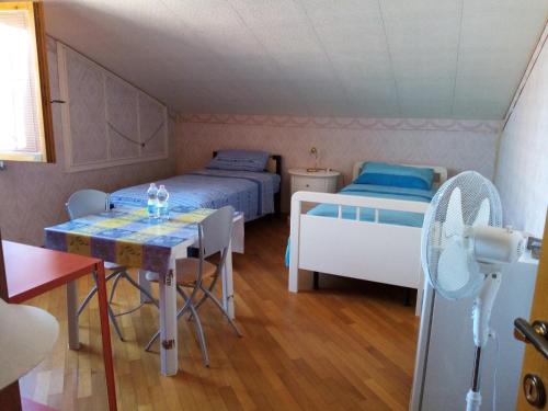 Cette petite chambre comprend deux lits, une table et une table. dans l'établissement "La Gardenia" Affittacamere, à Marina di Montemarciano
