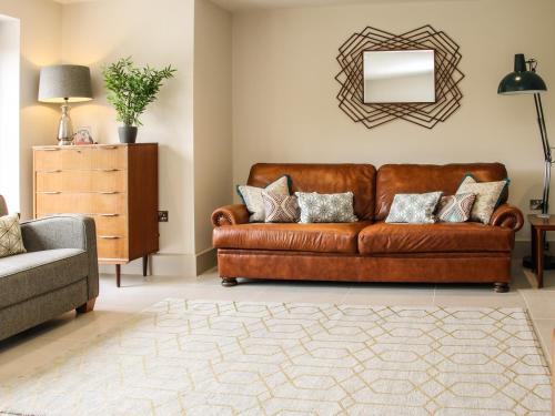 a living room with a brown couch and a mirror at The Wheatlands in Much Wenlock