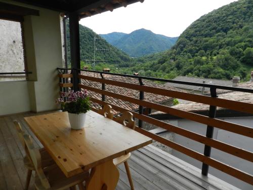 a wooden table on a balcony with a view of mountains at Ostello Sociale Borgo Venno in Lavenone