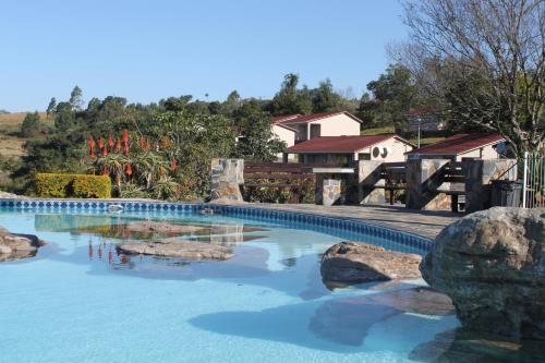 a swimming pool with blue water and rocks at Panorama Chalets & Rest Camp in Graskop