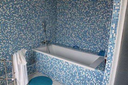 a blue tiled bathroom with a white bath tub at Holiday Home With Pool In Marseillan in Marseillan