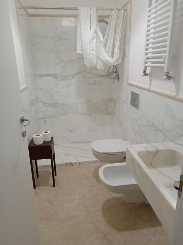 a white bathroom with a toilet and a sink at Hotel Caprice in Marina di Massa