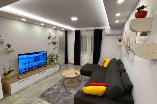 sala de estar con sofá negro y TV en Luxury APARTMAN BILI, en Podgora