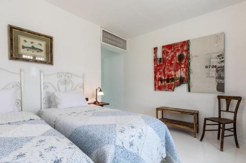 a white bedroom with two beds and a chair at Deniz Kabugu Hotel in Alacati