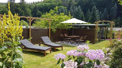 a garden with two chairs and a table with an umbrella at Ferienwohnung Papenmühle am Kurpark in Bad Freienwalde