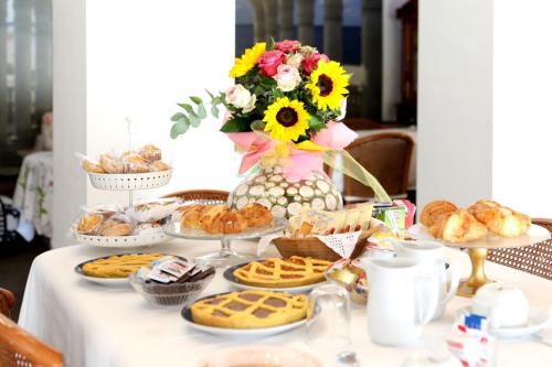a table with cookies and pastries and a vase of flowers at B&B Villa Floriana in Tortoreto Lido