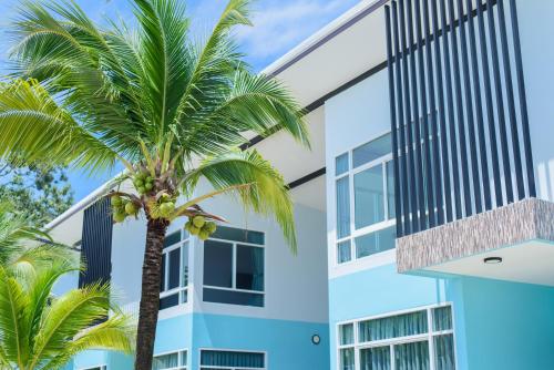 a palm tree in front of a building at หาดตื้น คลื่นสวย รีสอร์ท - Hadtuen Kluensuay Resort in Chao Lao Beach