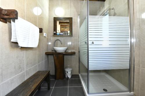 a bathroom with a shower and a sink and a bench at Tzlil Hateva in H̱osen