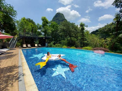 2 persone giocano in una piscina di Li River Resort a Yangshuo