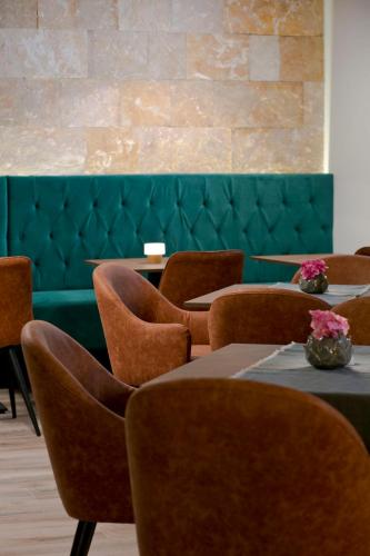 a dining room with tables and chairs and a green bench at B&B Plitvice Holiday Lodge in Plitvička Jezera