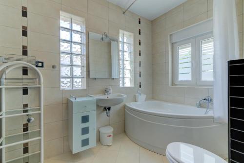 a white bathroom with a tub and a sink at Villa Dalmare in Novi Vinodolski